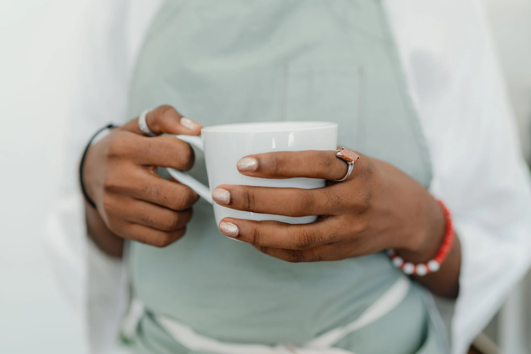 Close-up photograph of a café worker holding a white coffee cup